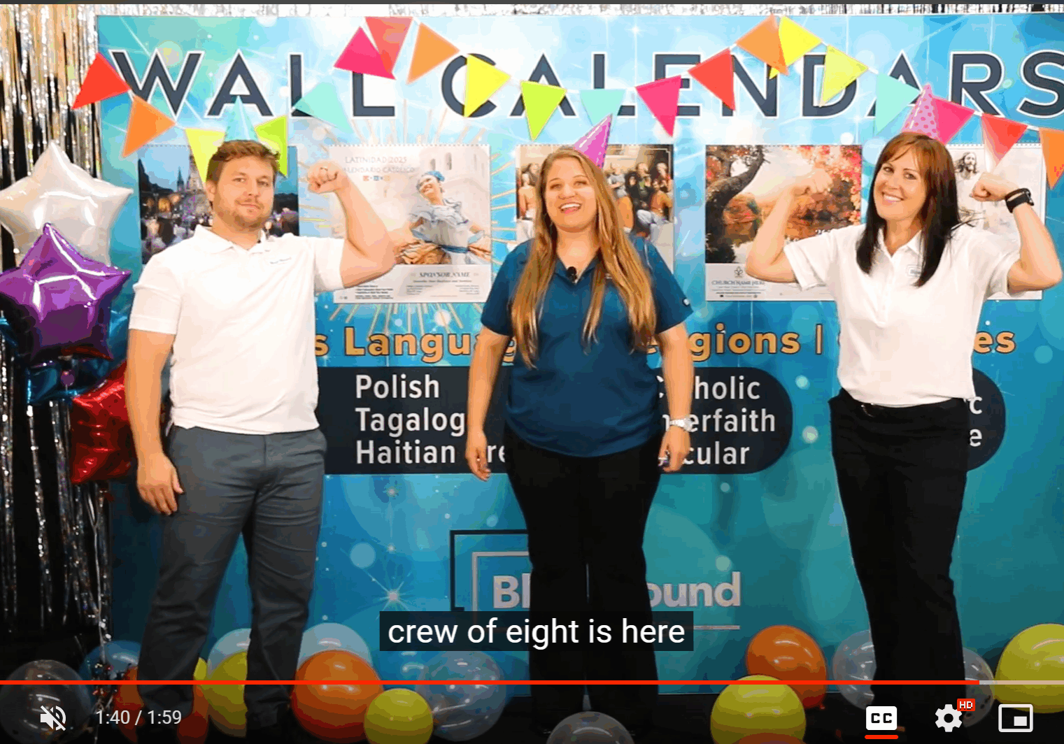Photo of a video playing. WIth a picture of three people standing in front of a tradeshow booth that looks like it is having a party.